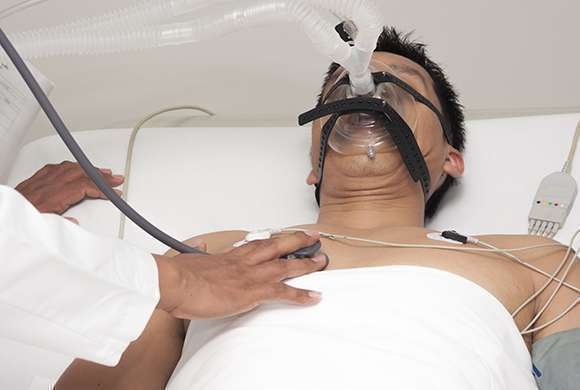 Paciente deitado em leito de hospital utilizando respirador artificial